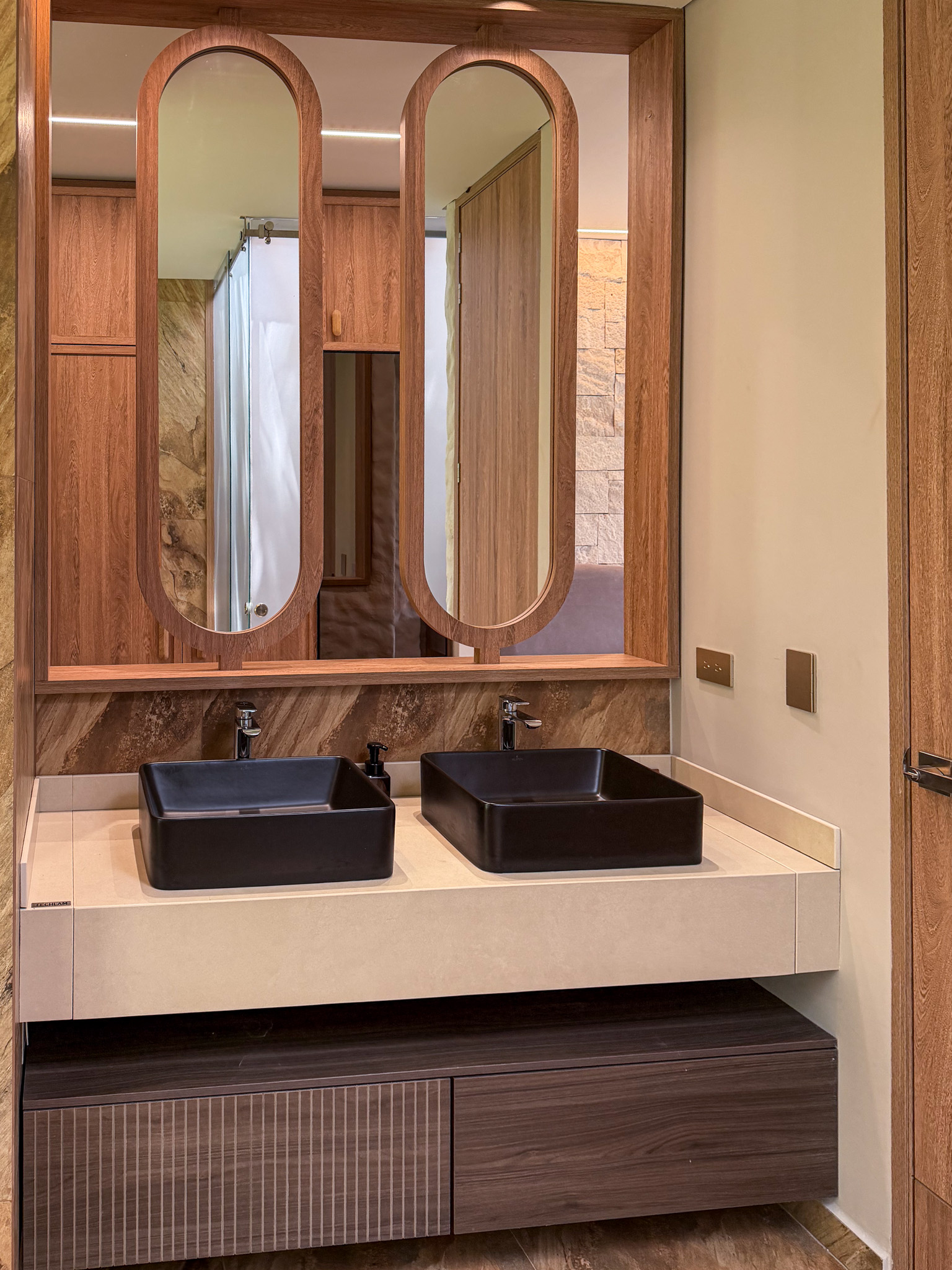 Madera, piedra y espejo en baño de Casa Colina